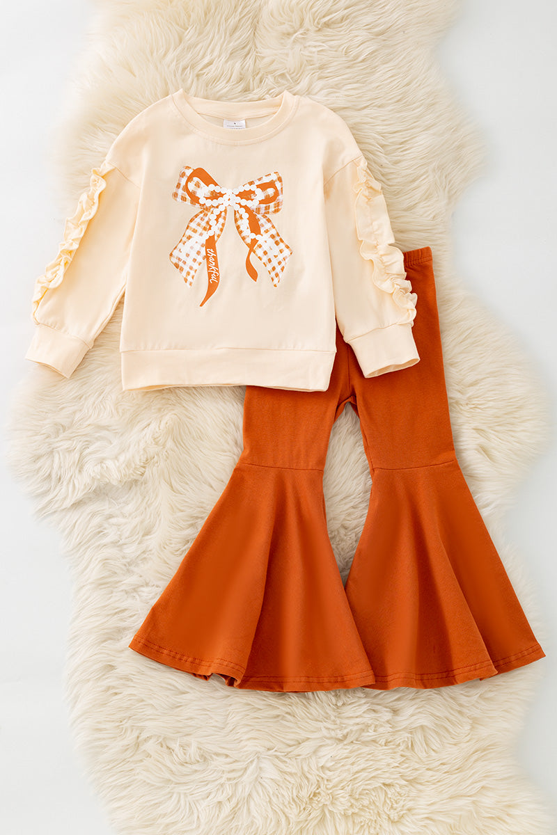 Pearl Bow printed on cream sweatshirt w/ ruffle and rust orange bell bottoms. OFG61417 SOL