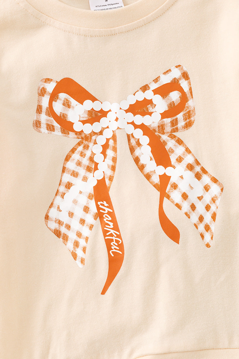 Pearl Bow printed on cream sweatshirt w/ ruffle and rust orange bell bottoms. OFG61417 SOL