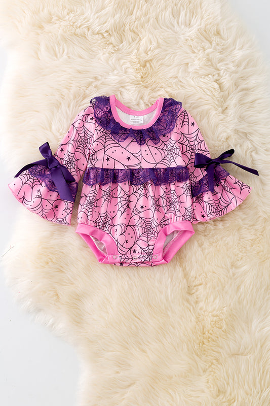 Spider web printed on pink baby onesie with purple lace and bell sleeves.