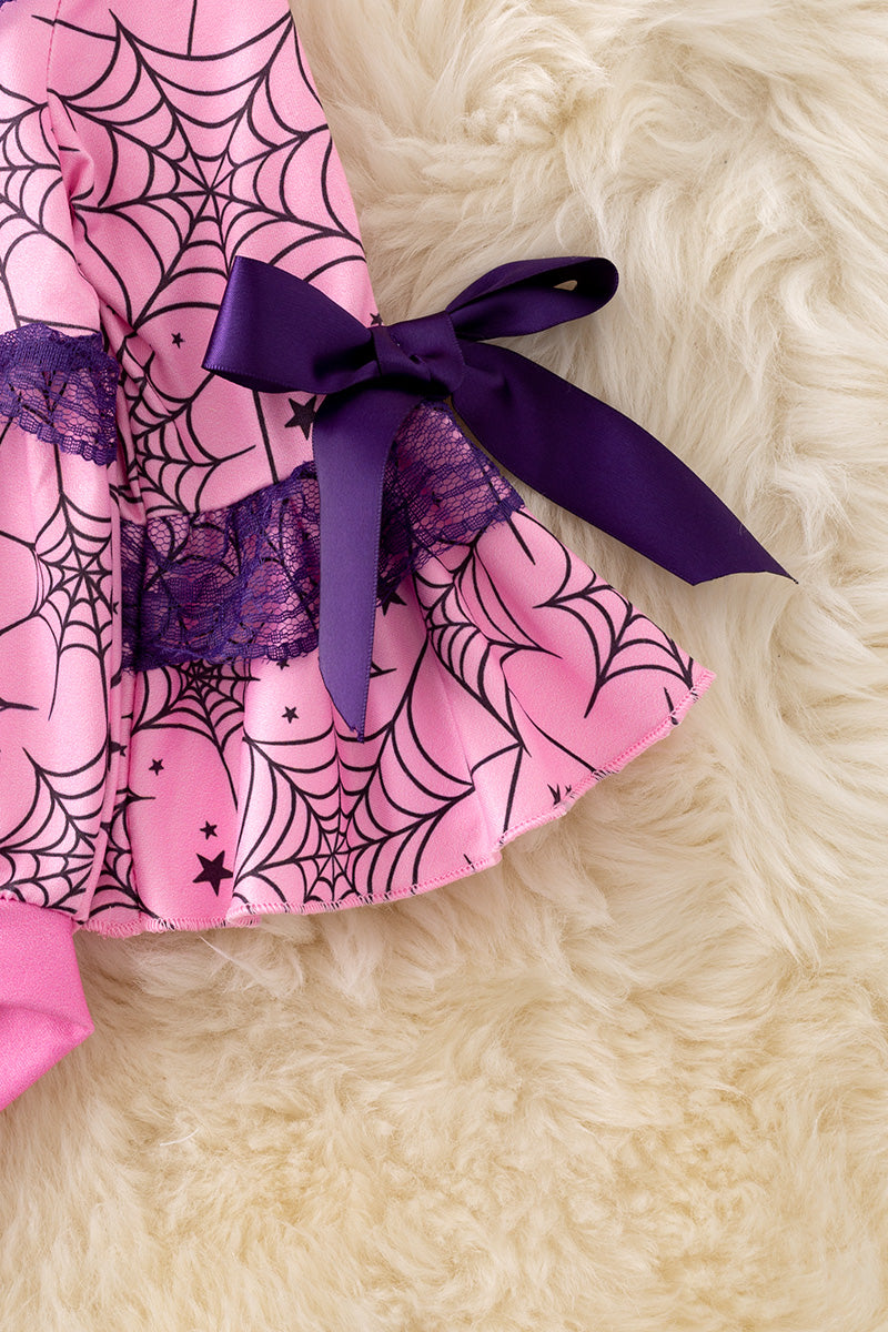 Spider web printed on pink baby onesie with purple lace and bell sleeves.