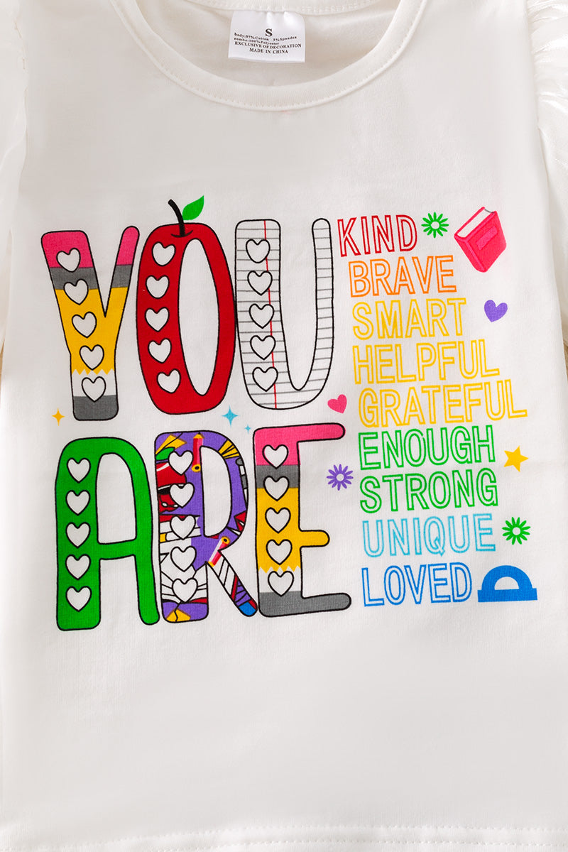 "You are kind, brave" white top w/ bubble sleeves and denim shorts.